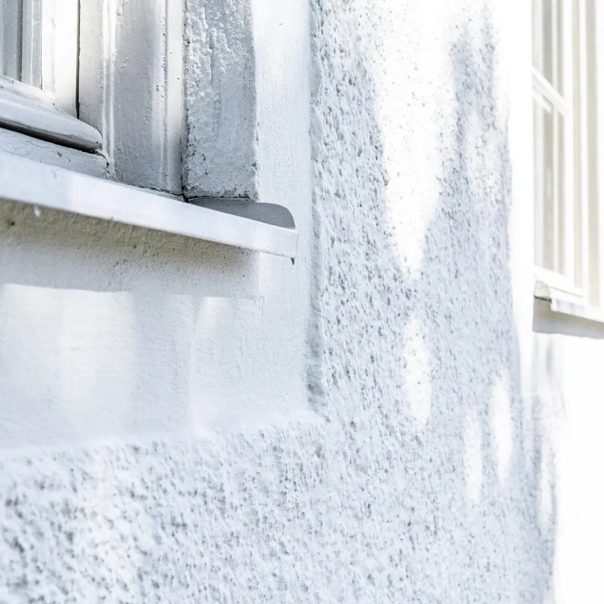 puts-fasadteknik-vit-husfasad-med-fonster-och-putsat-horn